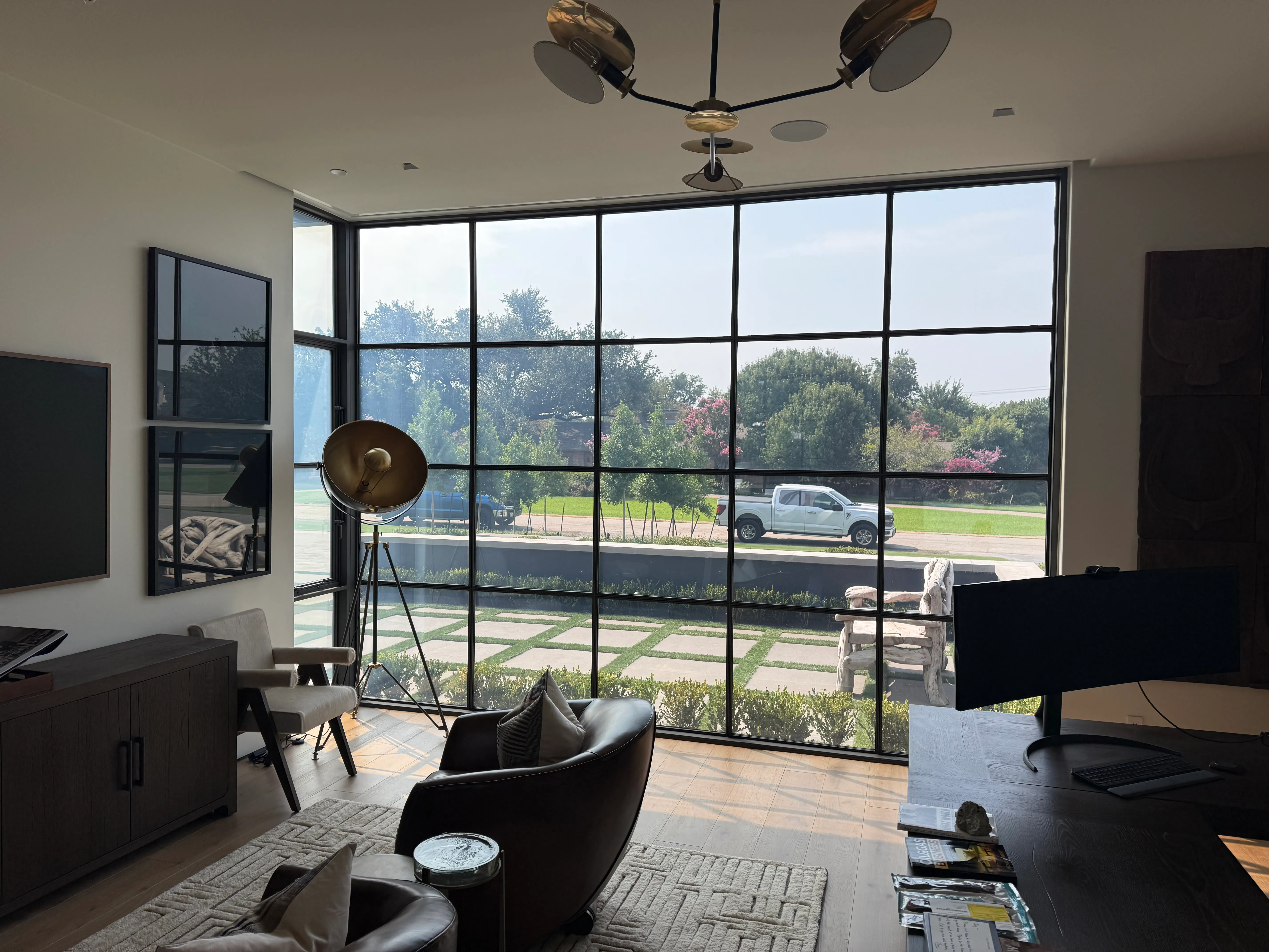 Living room with a Revive smart glass window wall in its clear state, overlooking the yard